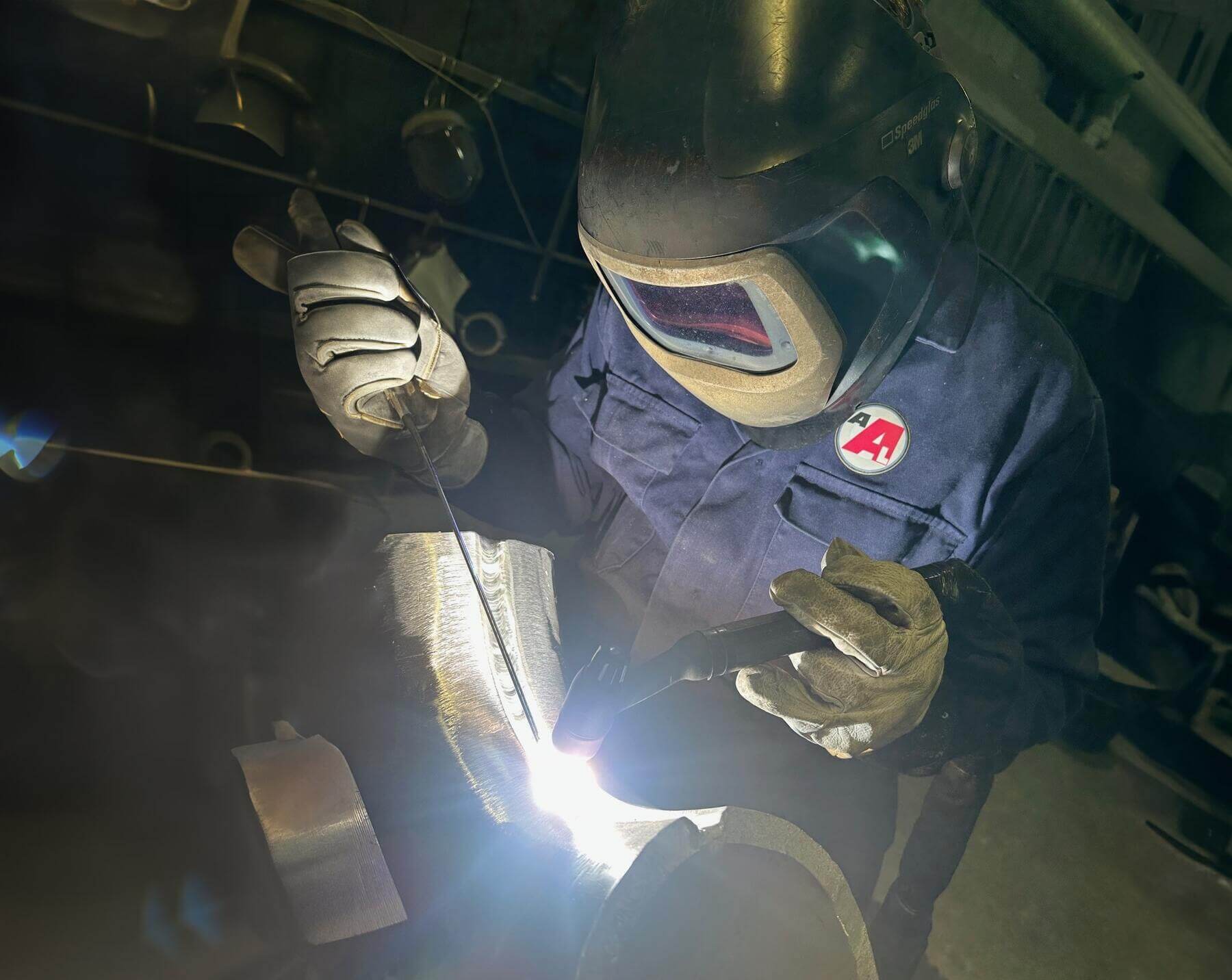 close up of a man welding together an aluminium pipe